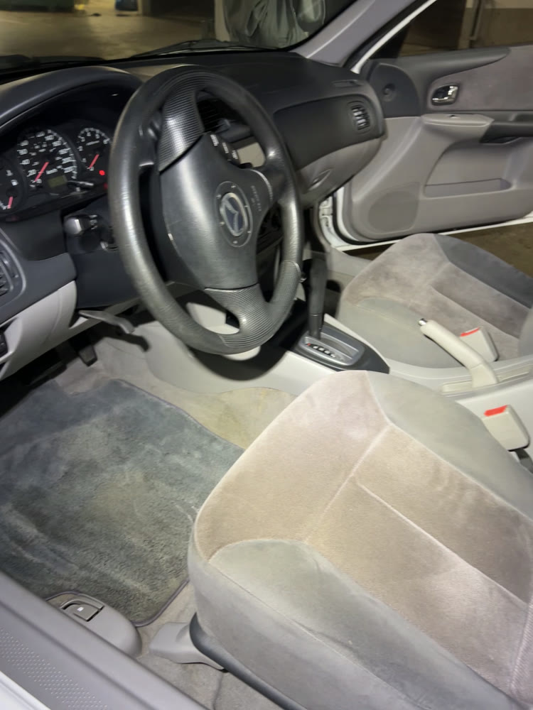 A sedan interior before cleaning — dusty dash and marked cloth seats
