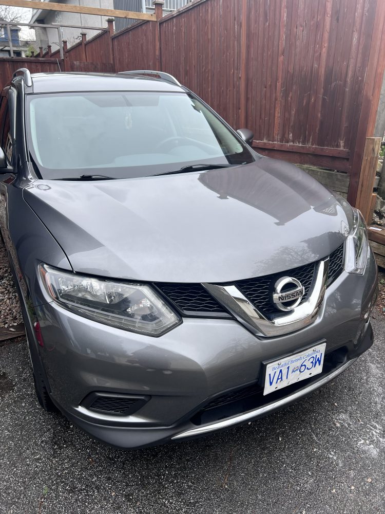 A grey Nissan Rogue parked beside a fence after a detail