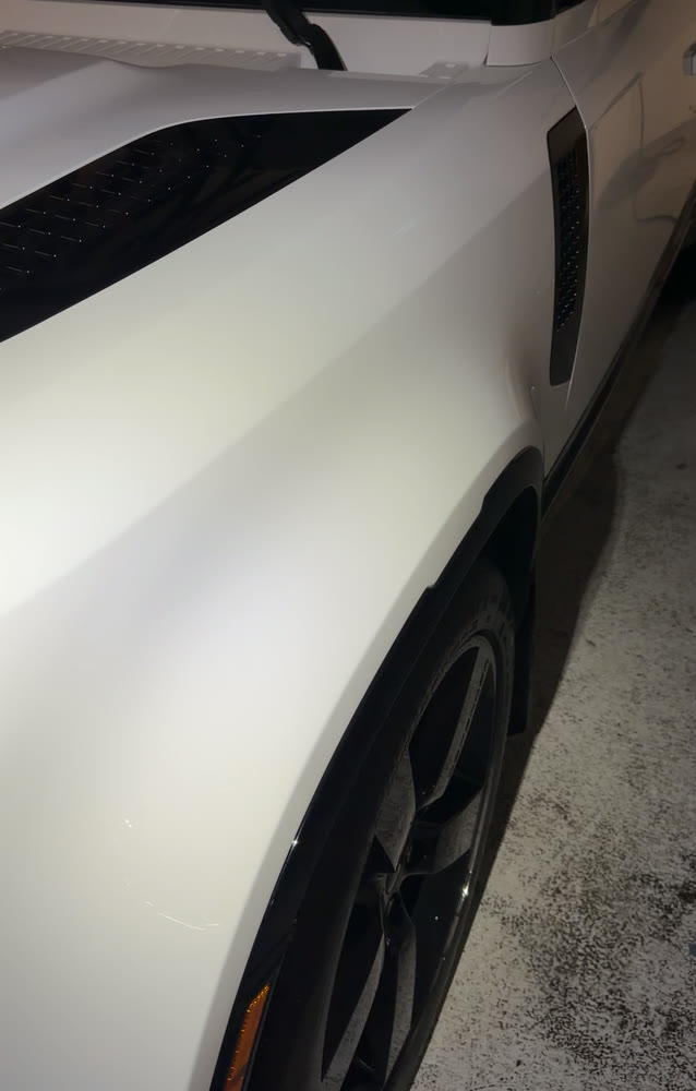 The rear quarter panel and wheel of a white sports car after paint work