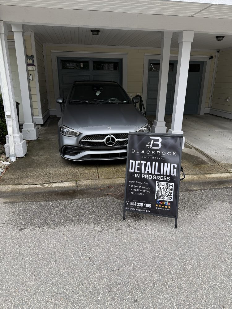 A silver Mercedes C-Class in a carport beside the Blackrock “detailing in progress” sign